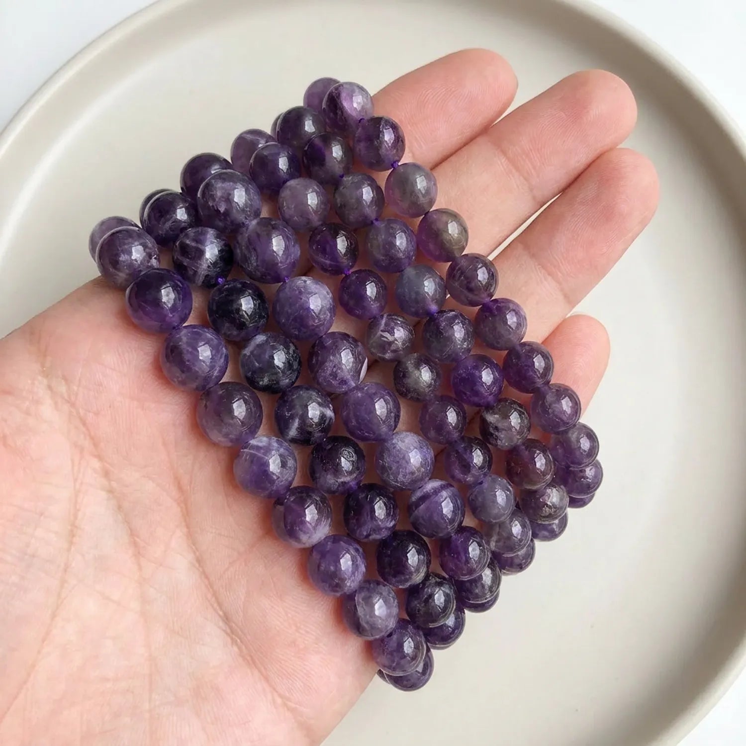 Natural amethyst beads shown in hand for size comparison