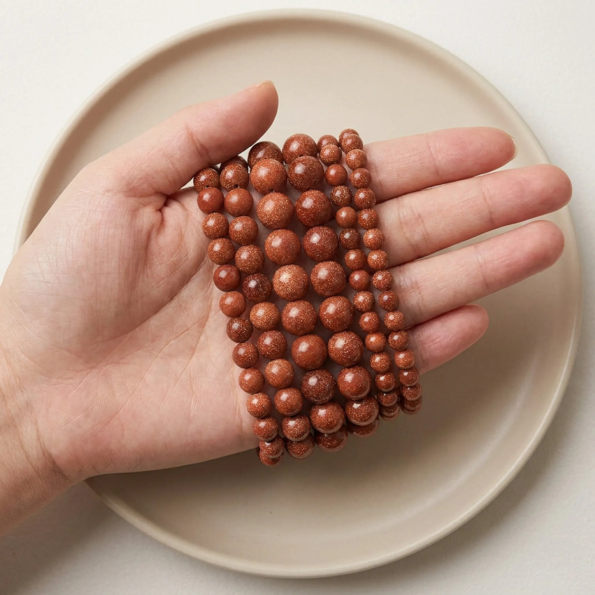 Gold sandstone beads shown in hand for size comparison