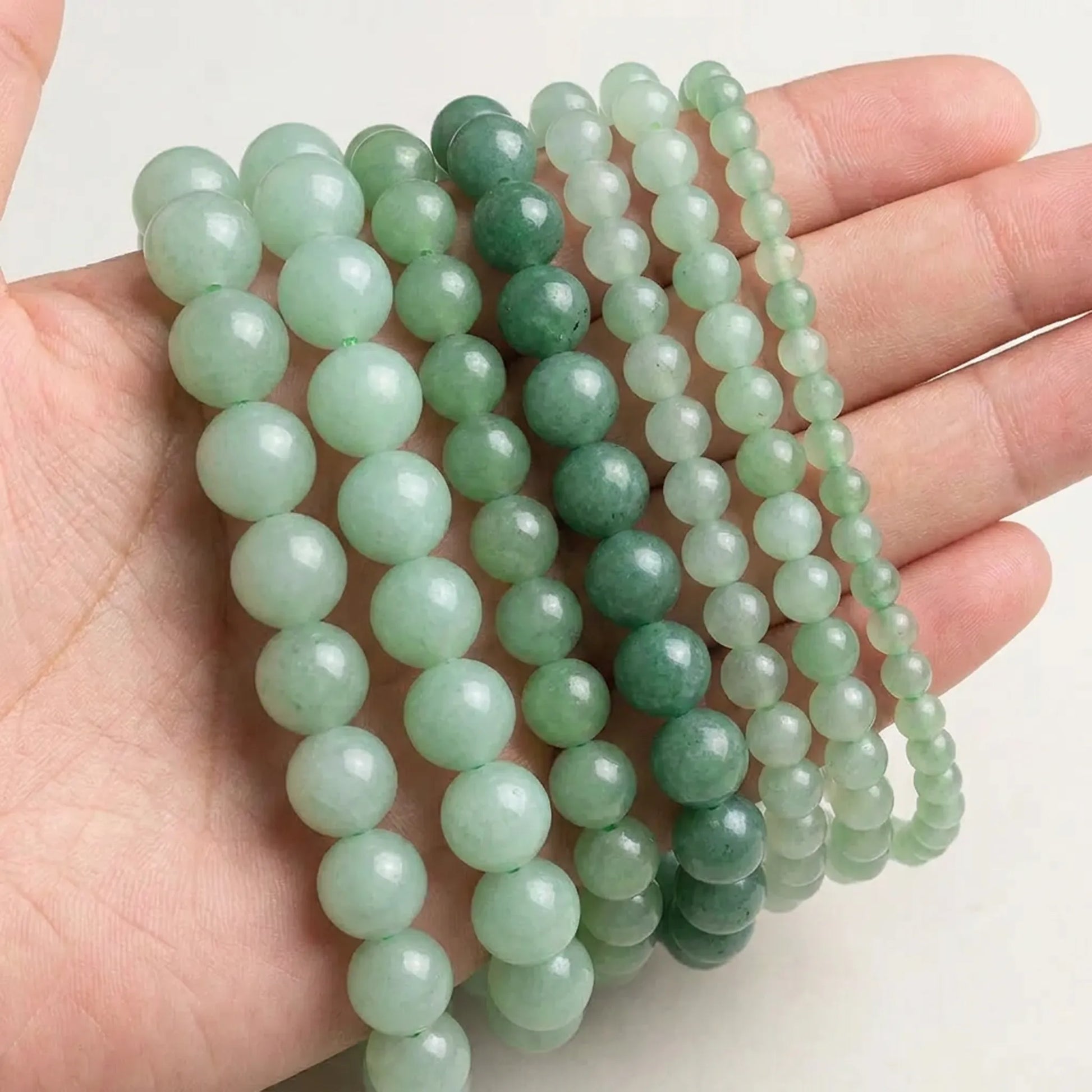 Natural green aventurine beads shown in hand for size comparison