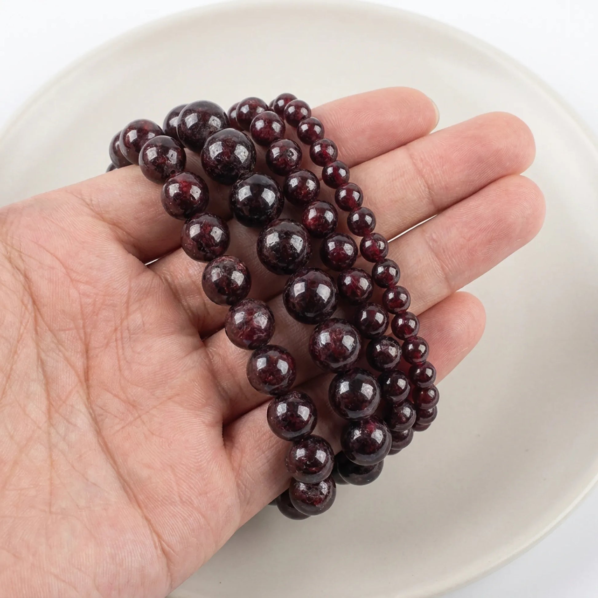 Natural red garnet beads shown in hand for size comparison