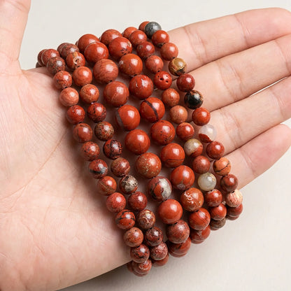 Natural red jasper beads shown in hand for size comparison