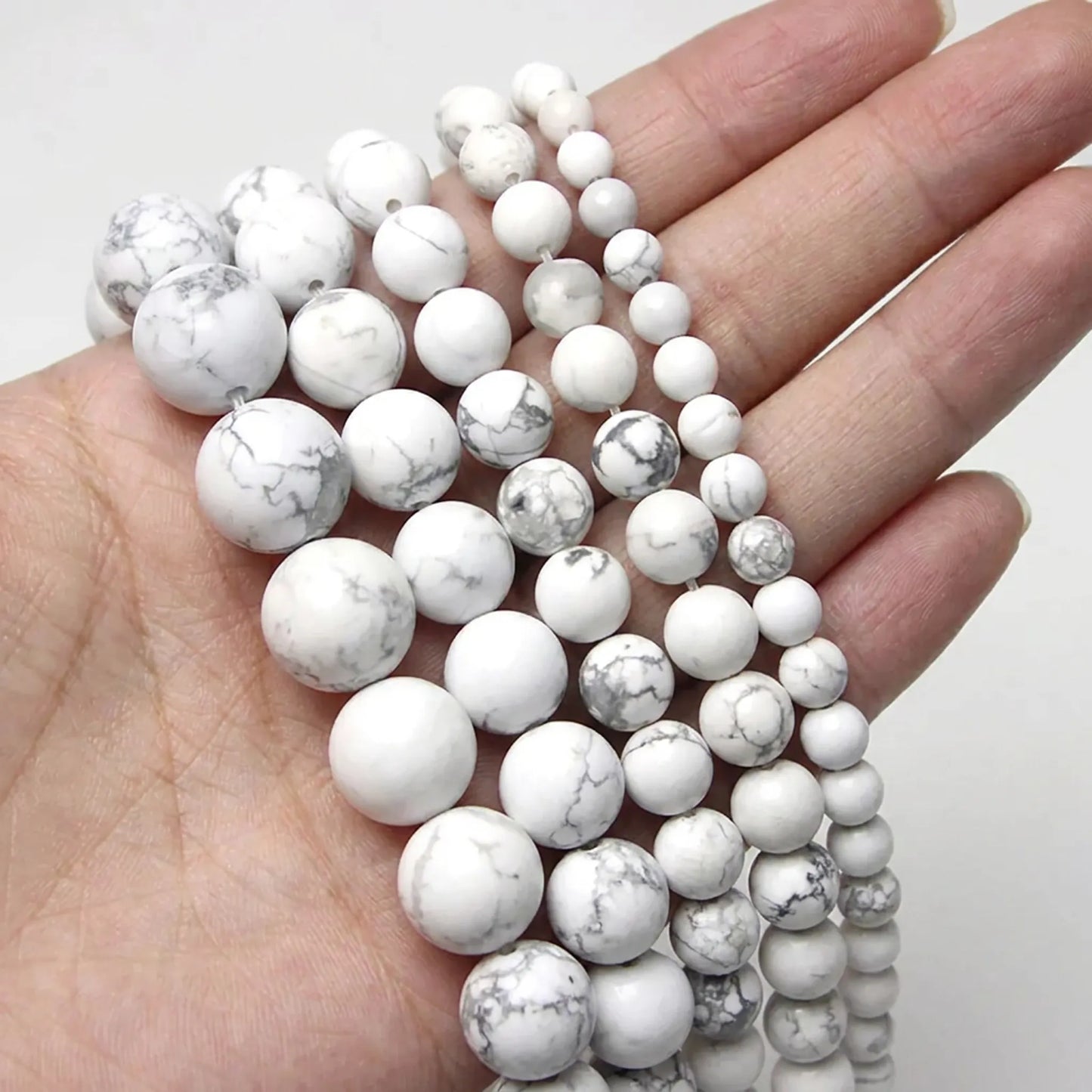 White turquoise howlite beads shown in hand for size comparison